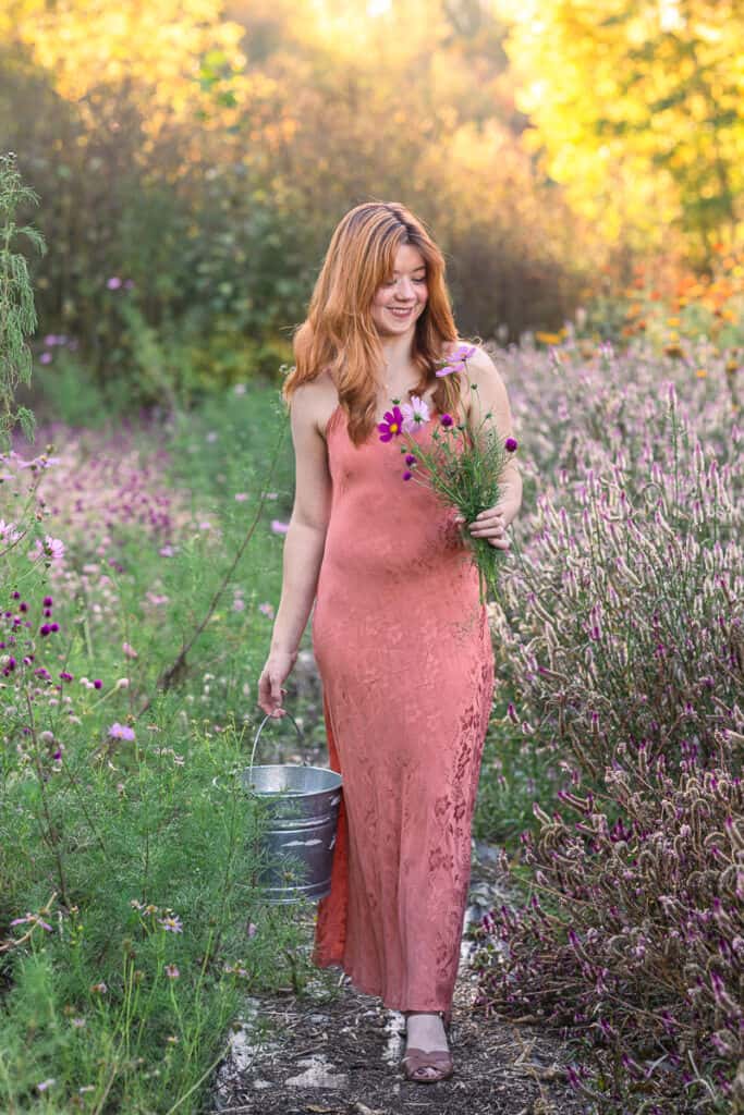 teen girl collects wildflower in satin dress